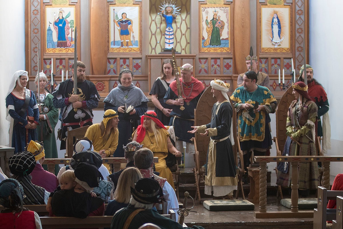 A king and queen hold court with assembled nobles.