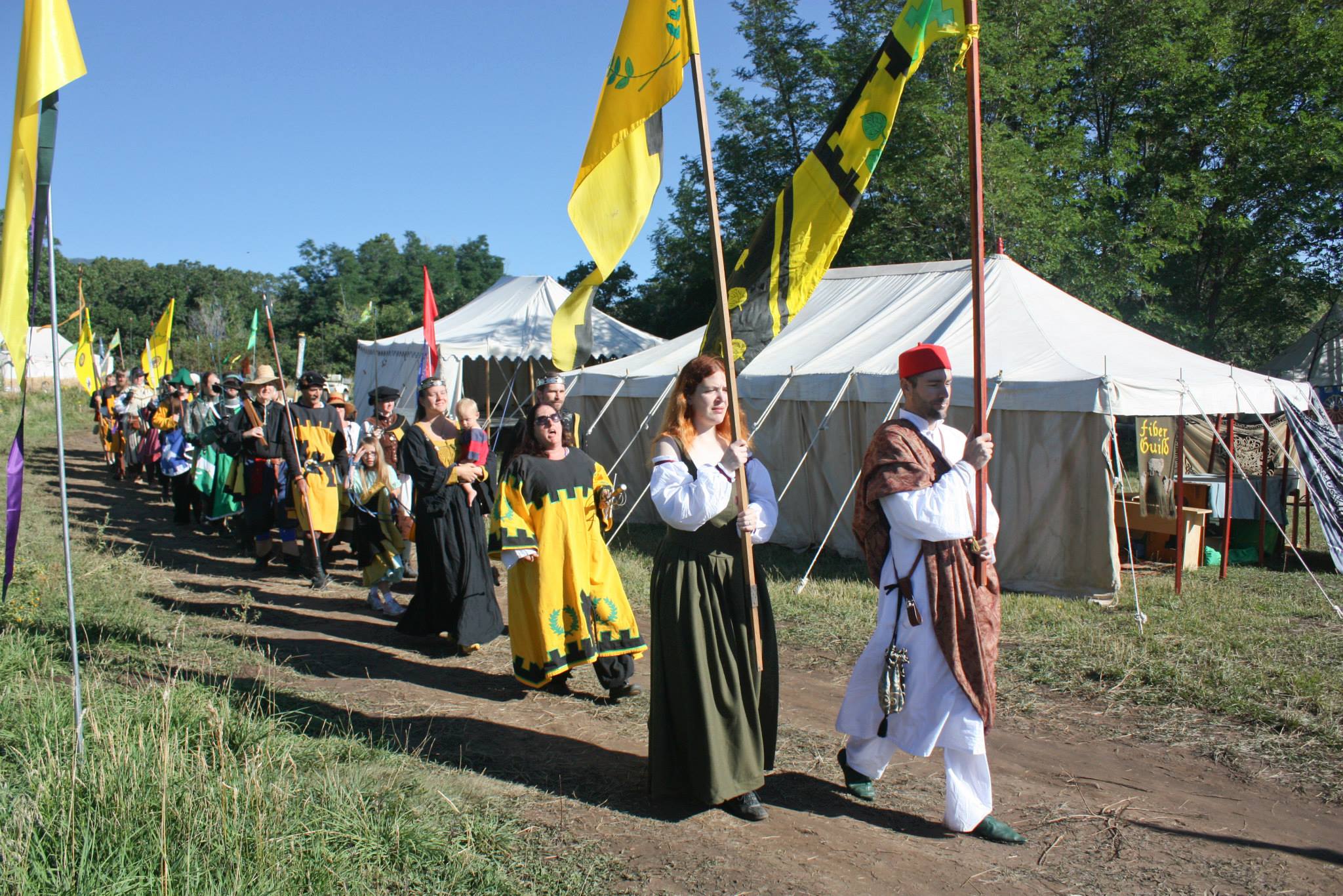 A procession of people with banners in front of a camp