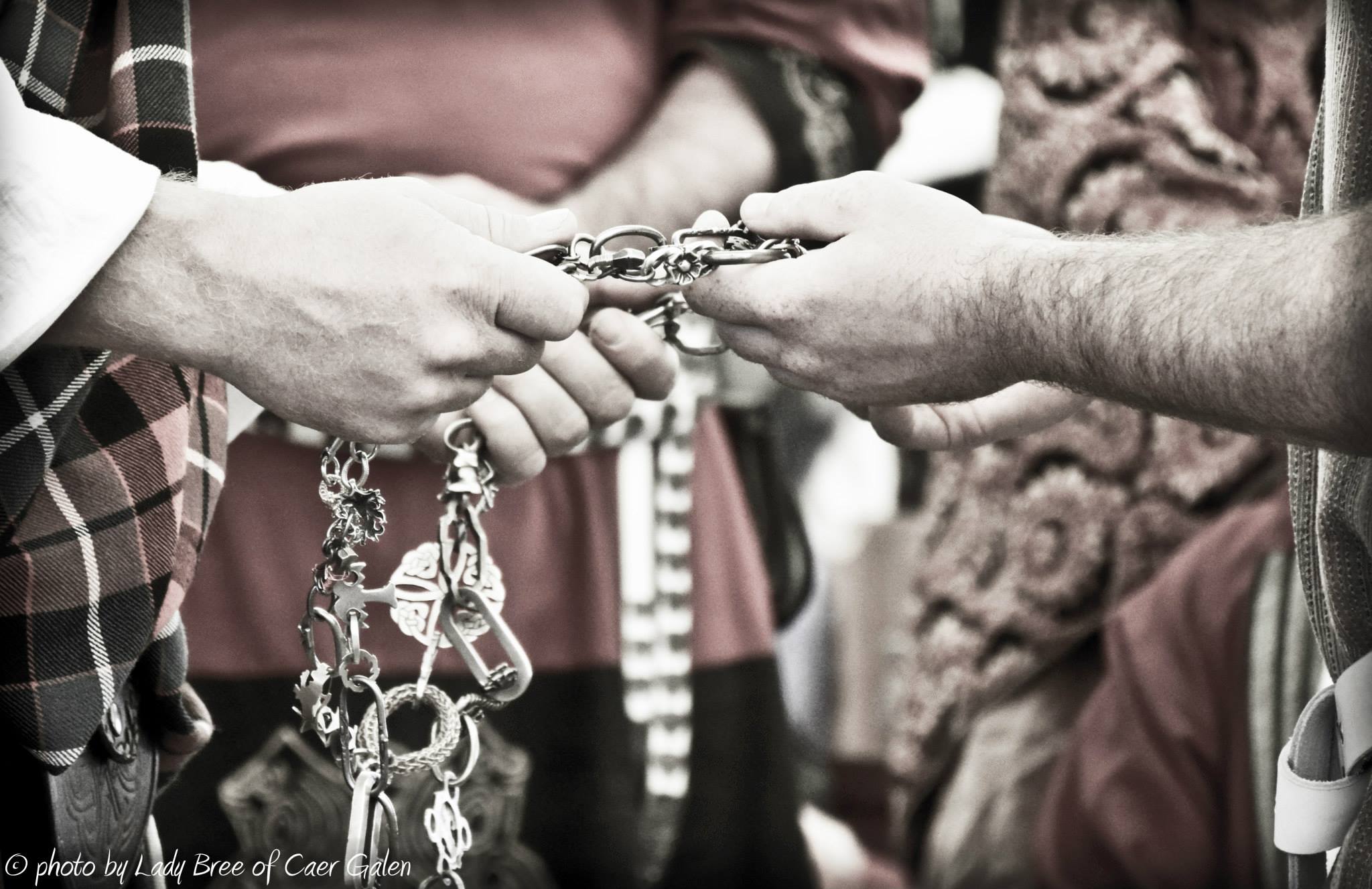 Two pairs of hands holding a decorative chain