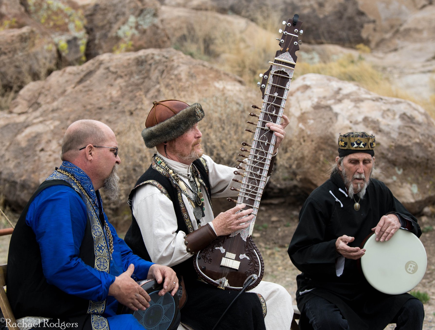 Three musicians playing drums and a sitar