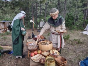 Two people getting food during a feast in the woods